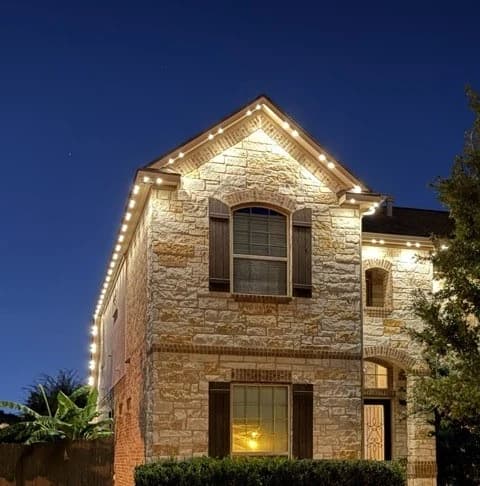 A TruLight gable in warm white, with light washing evenly down the stone and no bright cones under the lights