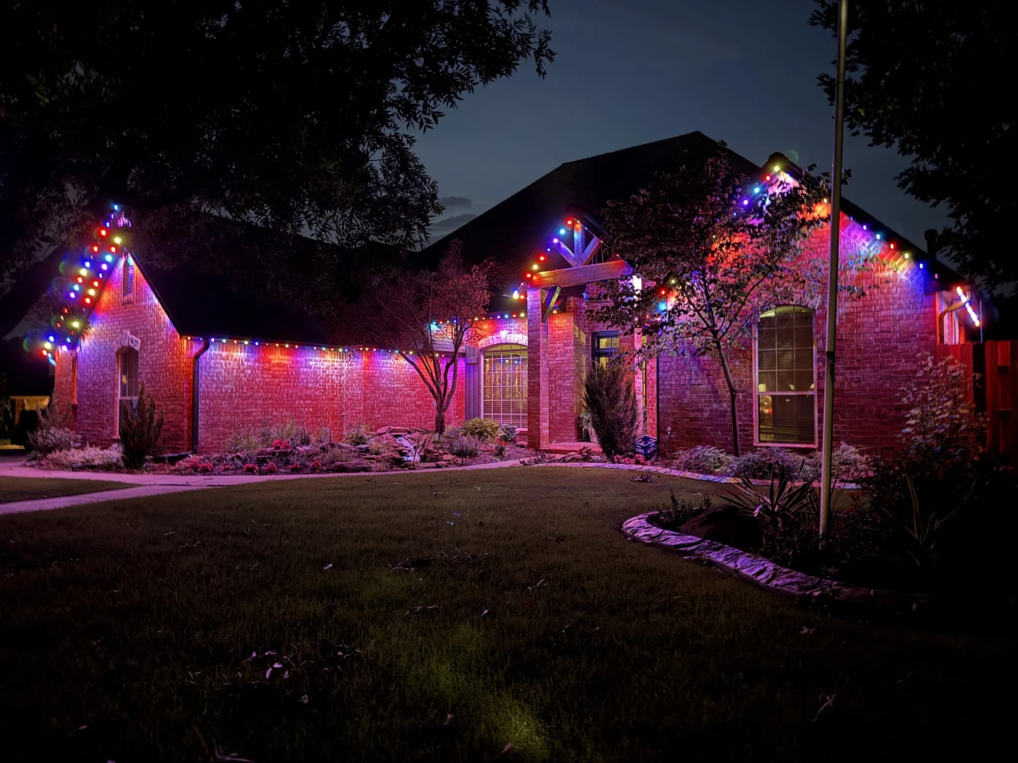 Multicolor TruLight roofline lights around a brick courtyard entry in Oklahoma.