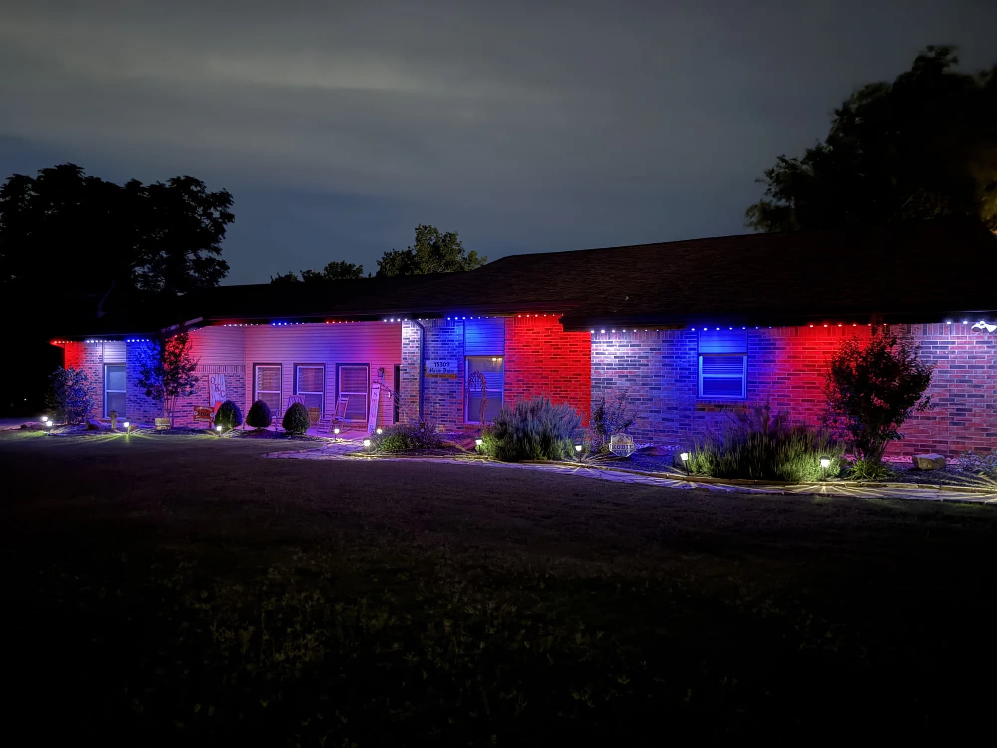 Red and blue TruLight accents across the front of a single-story brick home in Oklahoma.