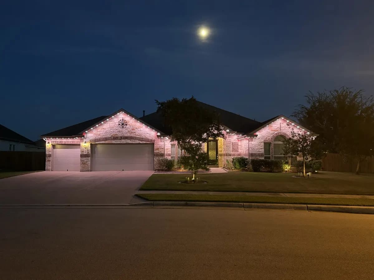 Pink TruLight roofline lighting on a single-story ranch home at dusk under a full moon.